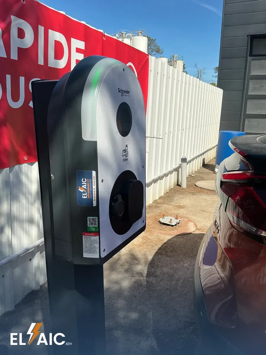Borne de recharge Schneider EVlink sur socle devant un garage automobile Citroën à Crozon, voyant vert, prise fermée