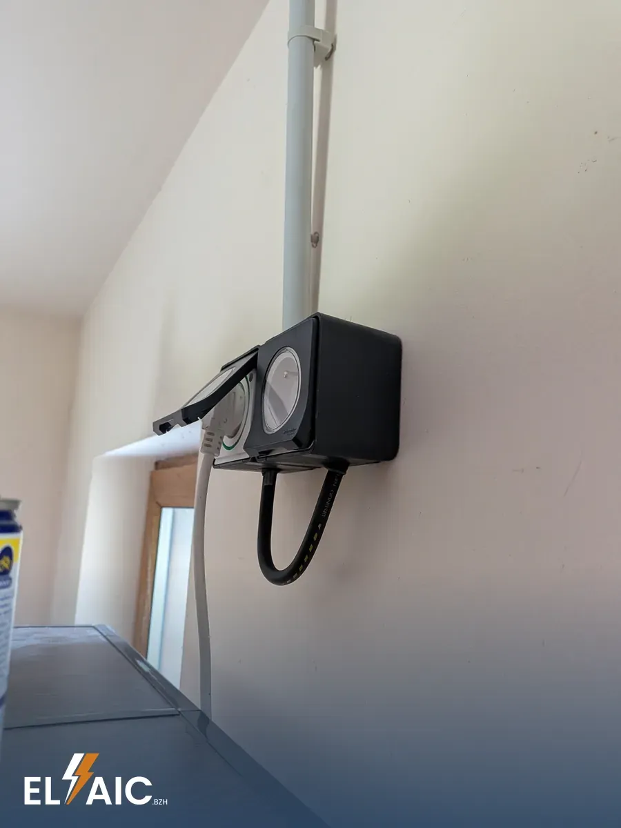 Prise électrique extérieure étanche installée en façade d'un garage à Plonévez-du-Faou